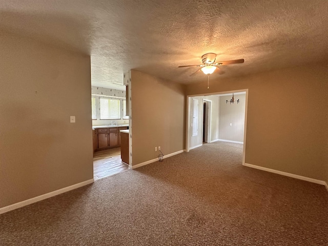 unfurnished living room with a textured ceiling, baseboards, dark carpet, and ceiling fan