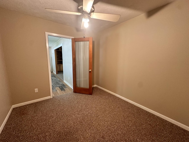 carpeted empty room featuring a textured ceiling, a ceiling fan, and baseboards