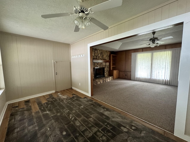 unfurnished living room featuring carpet flooring, a fireplace, a textured ceiling, and ceiling fan