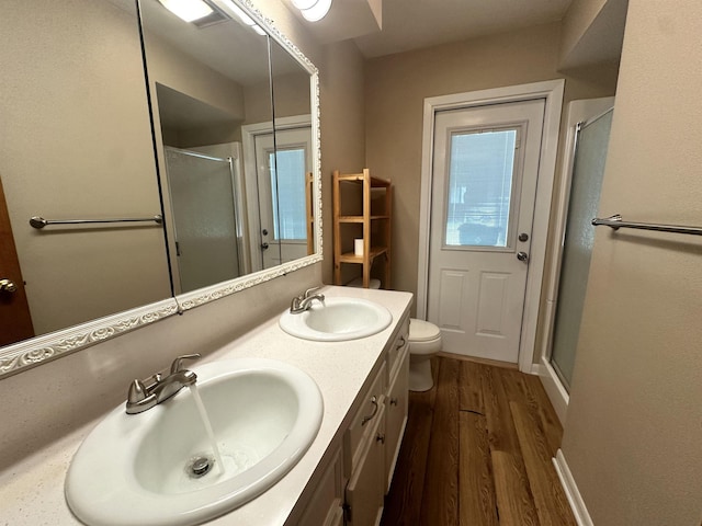 full bathroom with a sink, wood finished floors, a stall shower, and double vanity