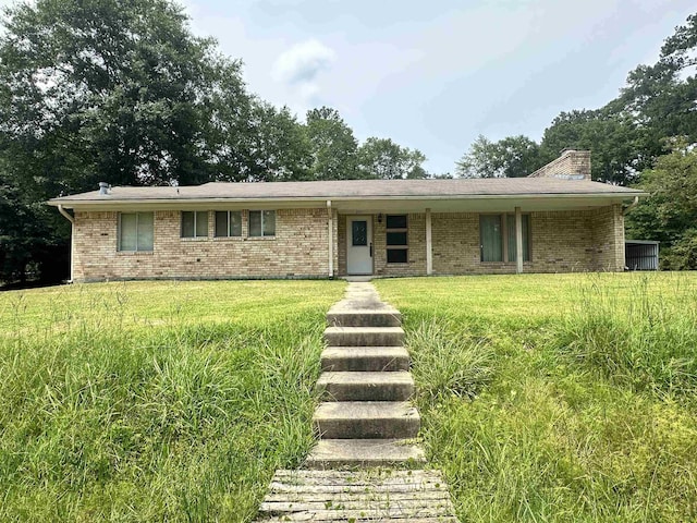 single story home featuring a front yard, brick siding, and a chimney