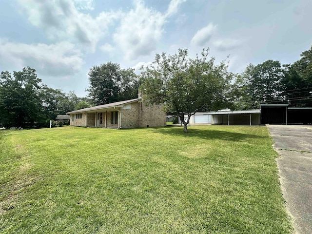 view of yard featuring a carport and concrete driveway