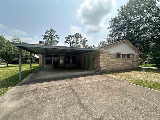 view of front of home featuring driveway, a front lawn, an attached carport, and brick siding