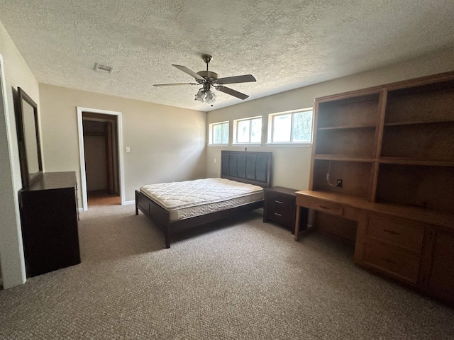 bedroom with visible vents, a ceiling fan, carpet flooring, and a textured ceiling