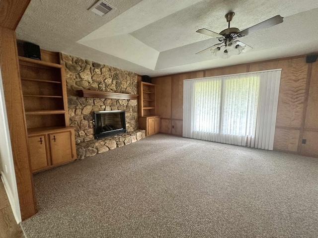 unfurnished living room with visible vents, a textured ceiling, carpet, a fireplace, and ceiling fan