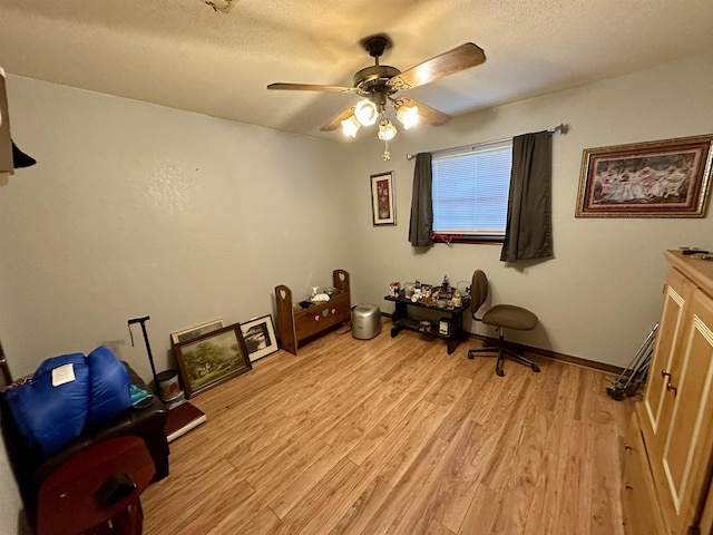 miscellaneous room featuring ceiling fan, light hardwood / wood-style floors, and a textured ceiling