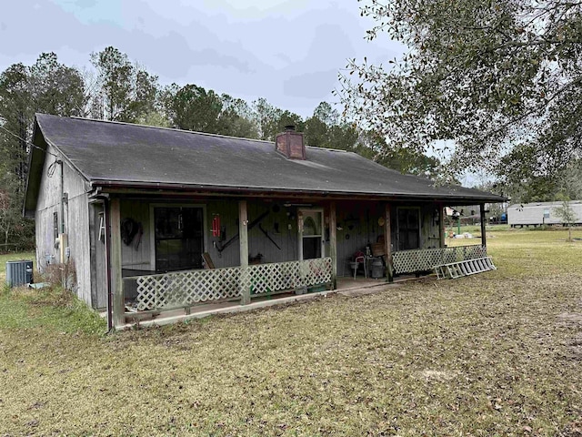 rear view of house with a porch, a yard, and central AC unit