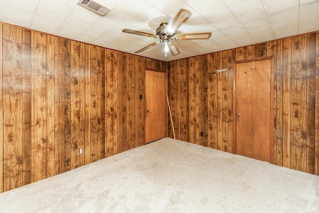 spare room with carpet flooring, wooden walls, and ceiling fan