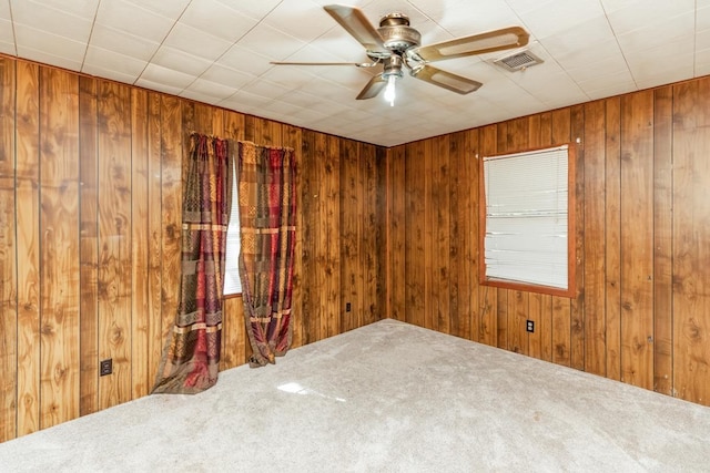 carpeted empty room featuring ceiling fan and wood walls