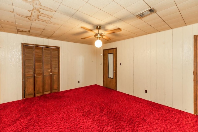 unfurnished bedroom with ceiling fan and wood walls