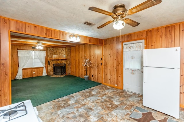 unfurnished living room with a textured ceiling, carpet floors, ceiling fan, and wooden walls