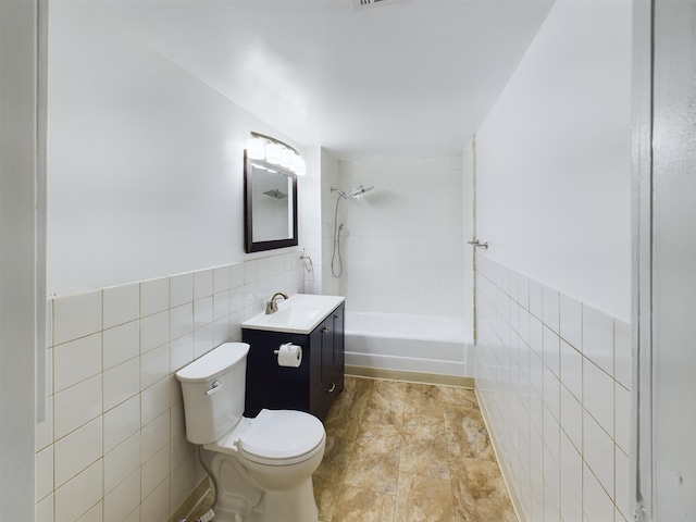 full bathroom featuring tile walls, vanity, tiled shower / bath combo, and toilet