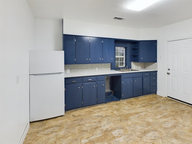 kitchen with white refrigerator, blue cabinetry, sink, and backsplash