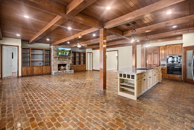 27076 Interstate 10, Winnie, TX 77665 - kitchen with black appliances, a brick fireplace, a kitchen island with sink, open shelves, and wooden ceiling with exposed beams