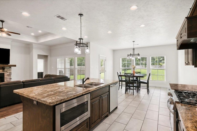 kitchen featuring visible vents, a sink, stainless steel appliances, a textured ceiling, and open floor plan