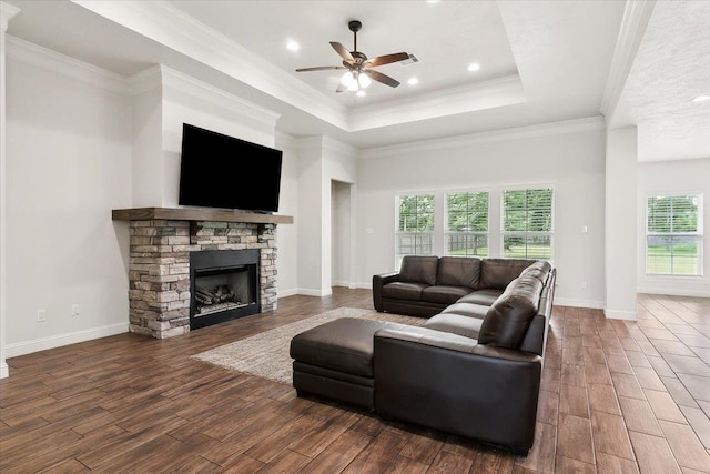 living area featuring a raised ceiling, ceiling fan, dark wood finished floors, and ornamental molding