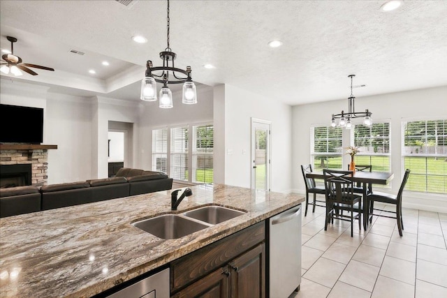 kitchen featuring dishwasher, a fireplace, open floor plan, and a sink