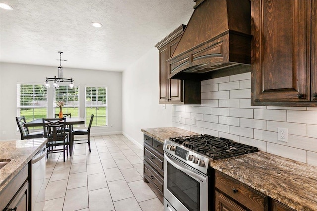 kitchen with tasteful backsplash, light stone countertops, custom range hood, an inviting chandelier, and stainless steel appliances