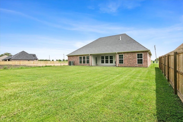 rear view of property with brick siding, a fenced backyard, a shingled roof, and a yard