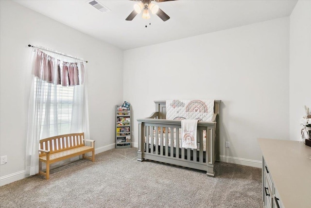 carpeted bedroom featuring a nursery area, baseboards, visible vents, and ceiling fan