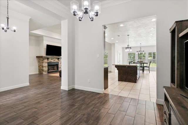 living area featuring a notable chandelier, a fireplace, baseboards, and wood finished floors