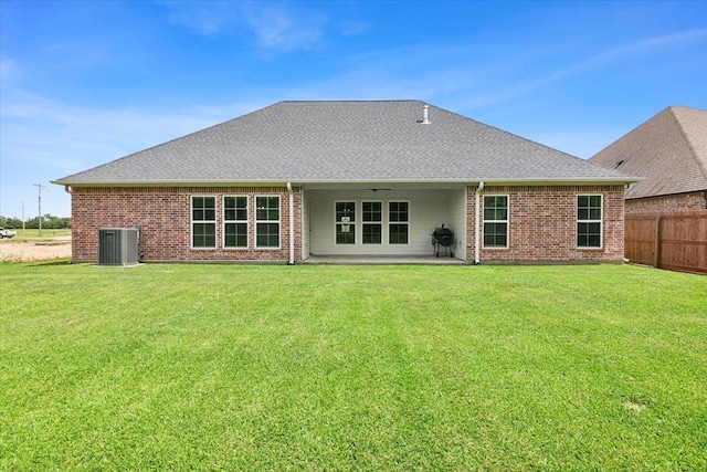 rear view of property featuring cooling unit, brick siding, and a lawn