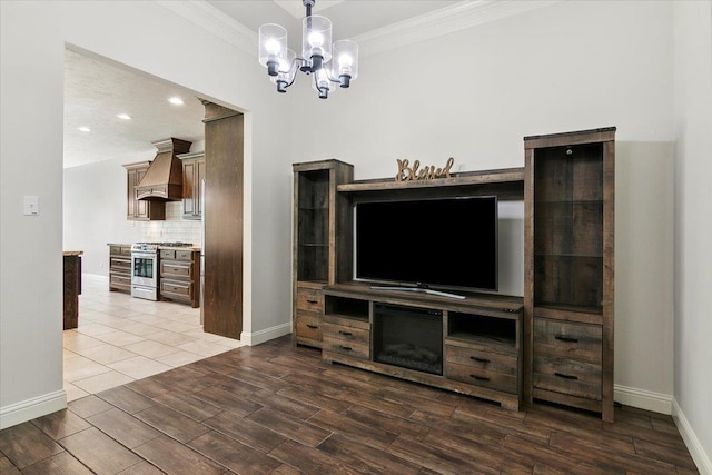 living area featuring a notable chandelier, ornamental molding, baseboards, and wood finished floors