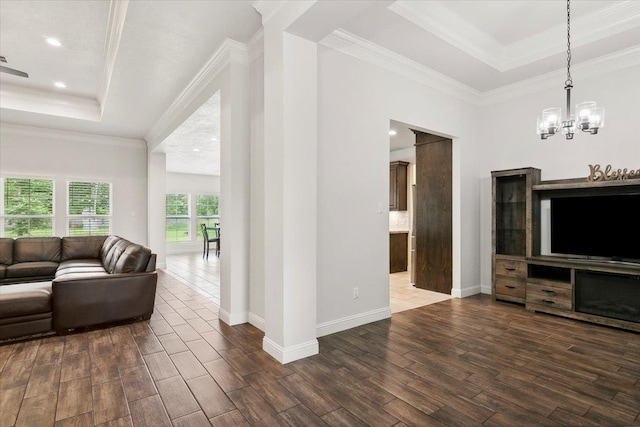 living room with dark wood finished floors, a notable chandelier, a raised ceiling, and ornamental molding