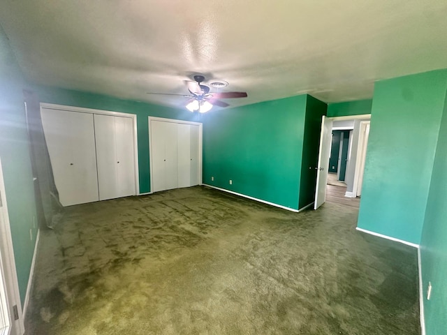 unfurnished bedroom with carpet floors, two closets, and ceiling fan