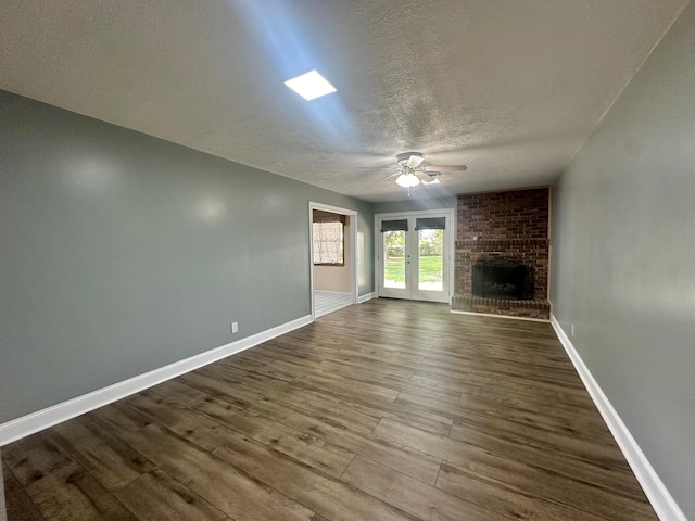 unfurnished living room with hardwood / wood-style floors, a textured ceiling, a brick fireplace, and ceiling fan