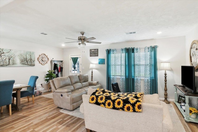 living room featuring ceiling fan, a textured ceiling, and light hardwood / wood-style flooring