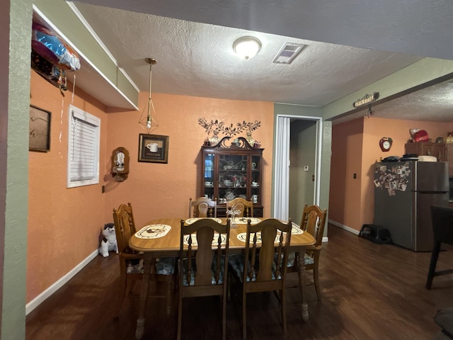 dining space with a textured ceiling and dark wood-type flooring