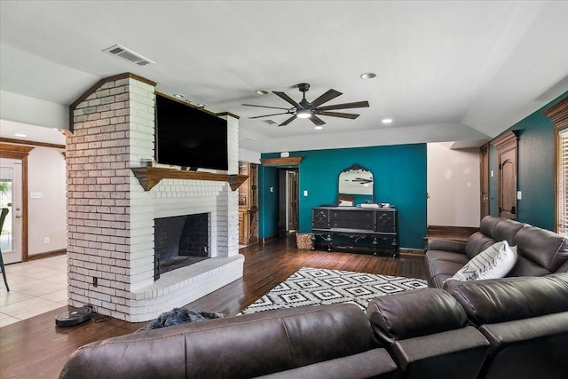 living room with hardwood / wood-style flooring, ceiling fan, lofted ceiling, and a fireplace