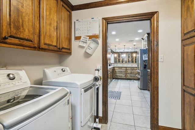 washroom featuring light tile patterned floors, washer and clothes dryer, and cabinets