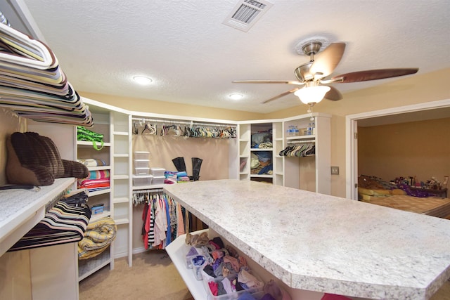 spacious closet with ceiling fan and light carpet