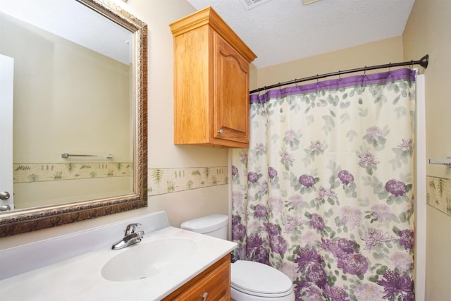 bathroom with a textured ceiling, vanity, toilet, and curtained shower