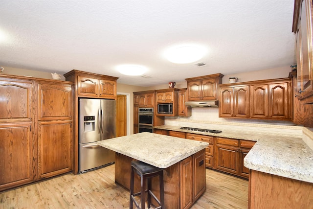 kitchen with a kitchen breakfast bar, light hardwood / wood-style floors, tasteful backsplash, a kitchen island, and stainless steel appliances