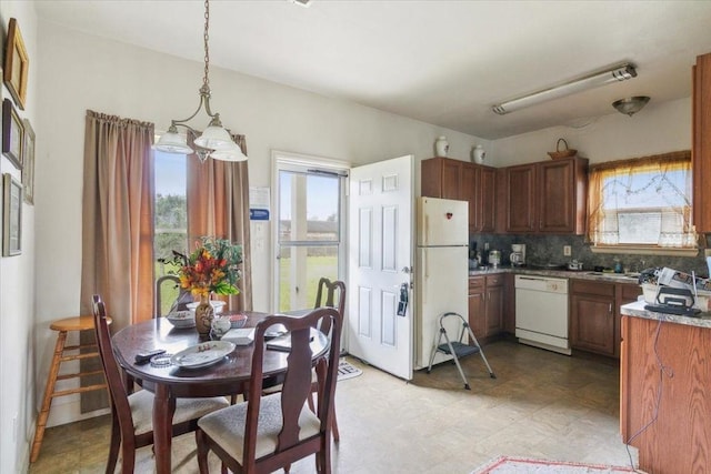 kitchen with hanging light fixtures, white appliances, sink, and decorative backsplash