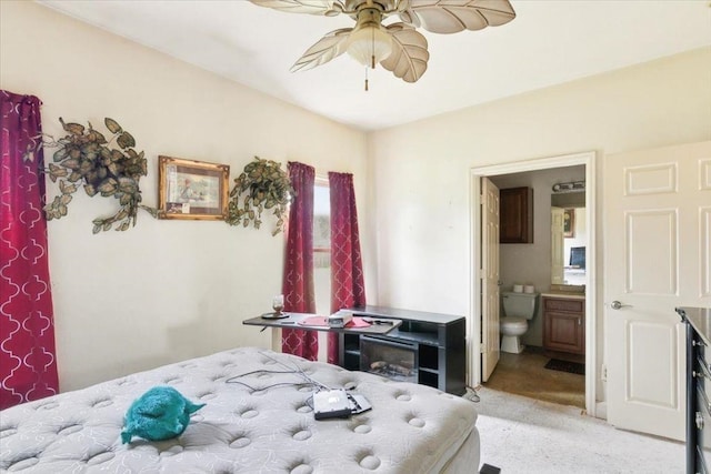 bedroom with connected bathroom, light colored carpet, and ceiling fan