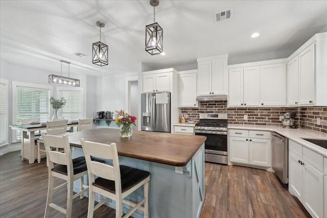 560 Lyndale St, Vidor, TX 77662 - kitchen with stainless steel appliances, wooden counters, tasteful backsplash, white cabinetry, and a kitchen breakfast bar