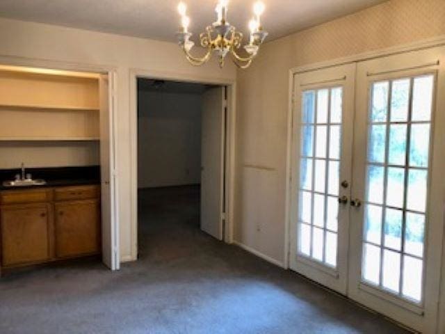 interior space with french doors, carpet floors, a notable chandelier, and sink