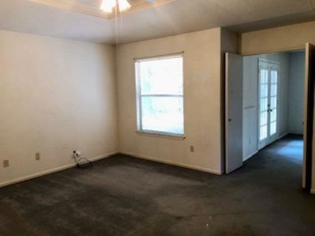 empty room with ceiling fan, french doors, and dark carpet