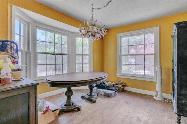 dining area with plenty of natural light, light wood-type flooring, and an inviting chandelier