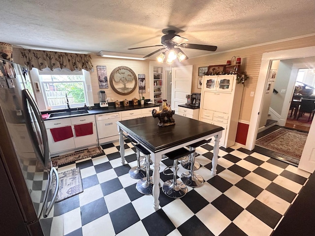 kitchen featuring white appliances, white cabinets, sink, ornamental molding, and a textured ceiling