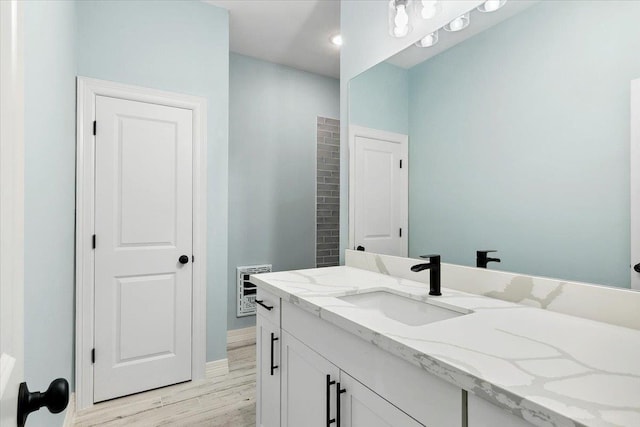 bathroom with hardwood / wood-style flooring, vanity, and heating unit