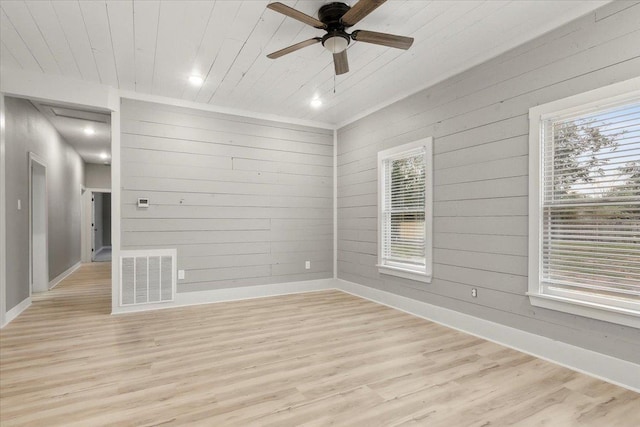 empty room with light wood-type flooring, wooden walls, ceiling fan, and wooden ceiling