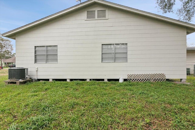 view of side of home with central AC unit and a lawn