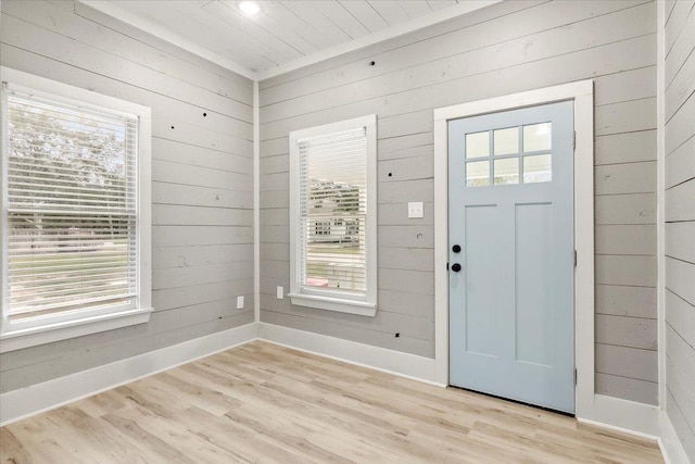 entryway with plenty of natural light, wood walls, and light hardwood / wood-style floors