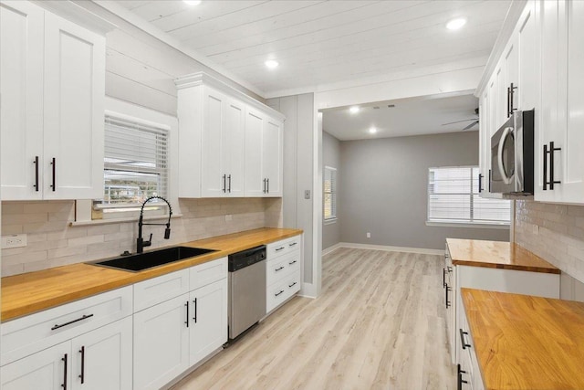 kitchen featuring wood counters, appliances with stainless steel finishes, sink, light hardwood / wood-style floors, and white cabinetry