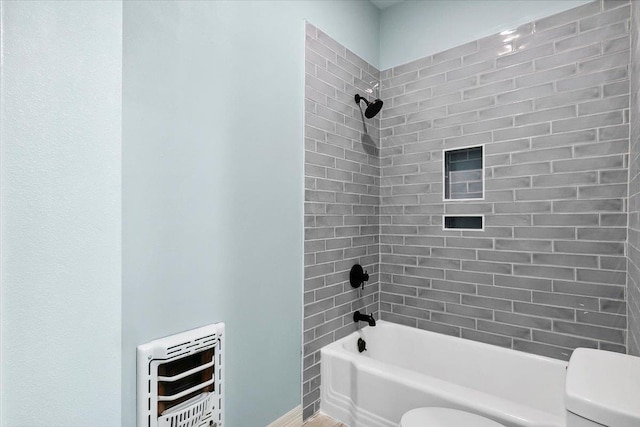 bathroom featuring tiled shower / bath combo, heating unit, and toilet